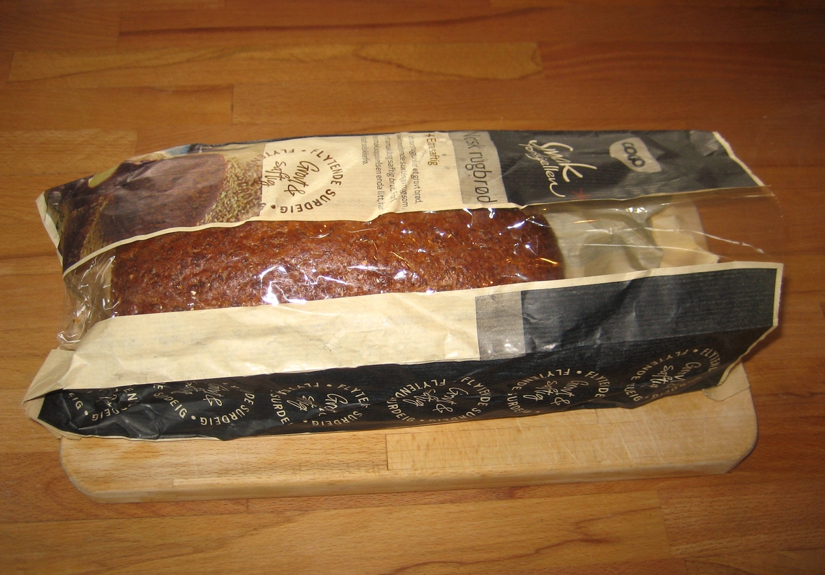 Motiv på posen er brød. Det ligger to skiver foran et oppskåret brød.  Ved siden av brødet er en bolle med smør, der det er plassert en kniv.