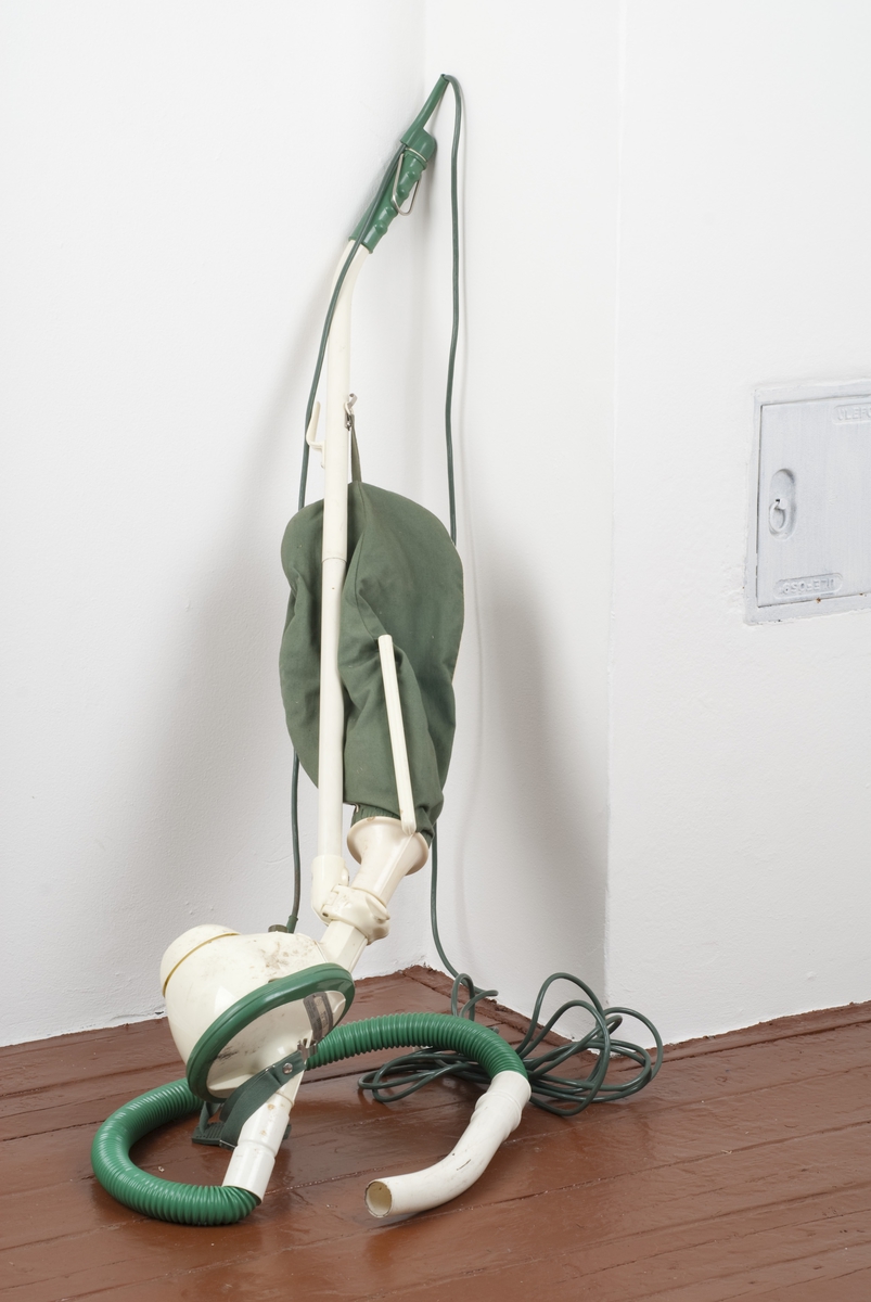 En støvsuger (A) av plast og tekstil i fargene grønn og hvit.
Det følger med to munnstykker B og C til støvsugeren. Del B er kort og bred, del C er lang og smal.
