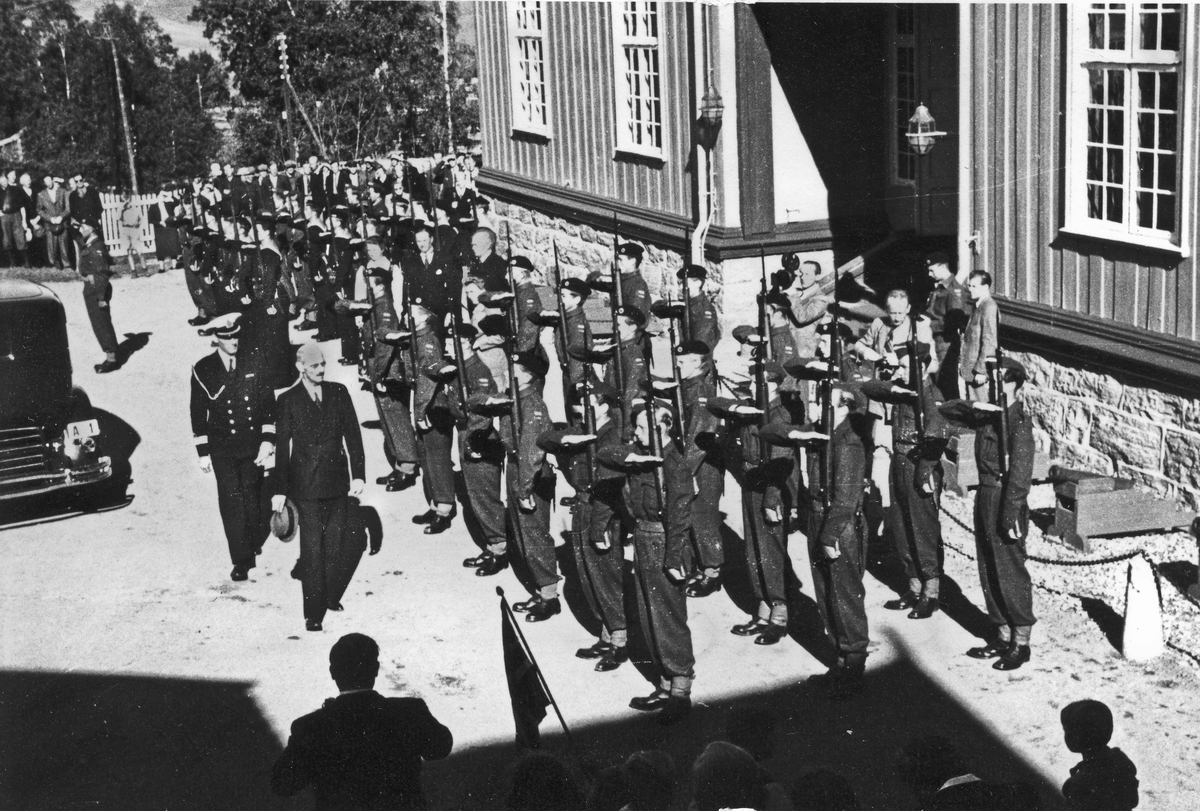 Kong Haakon inspiserer soldater ved Eidsvollbygningen. Det er usikkert i hvilken anledning. Like etter krigen – se uniformene.