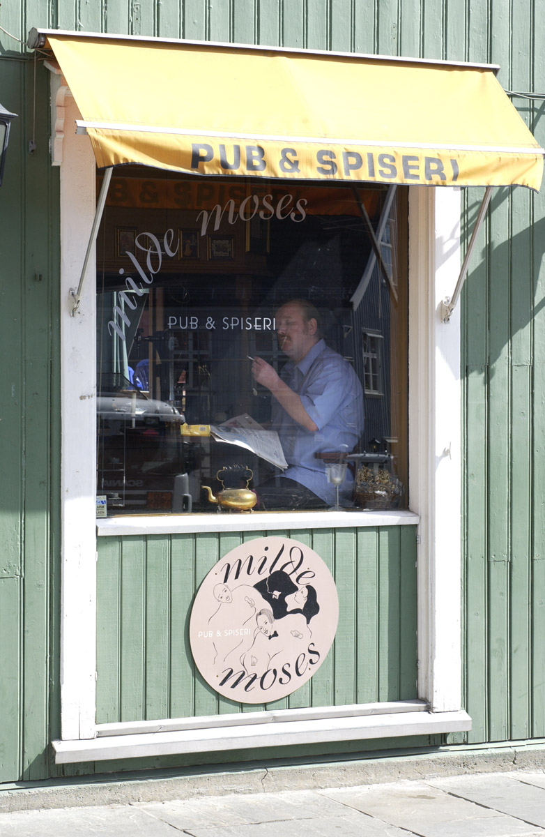 Pubgjest med røyk, øl og avis ses i vinduet til Milde Moses Pub & Spiseri i Drøbak