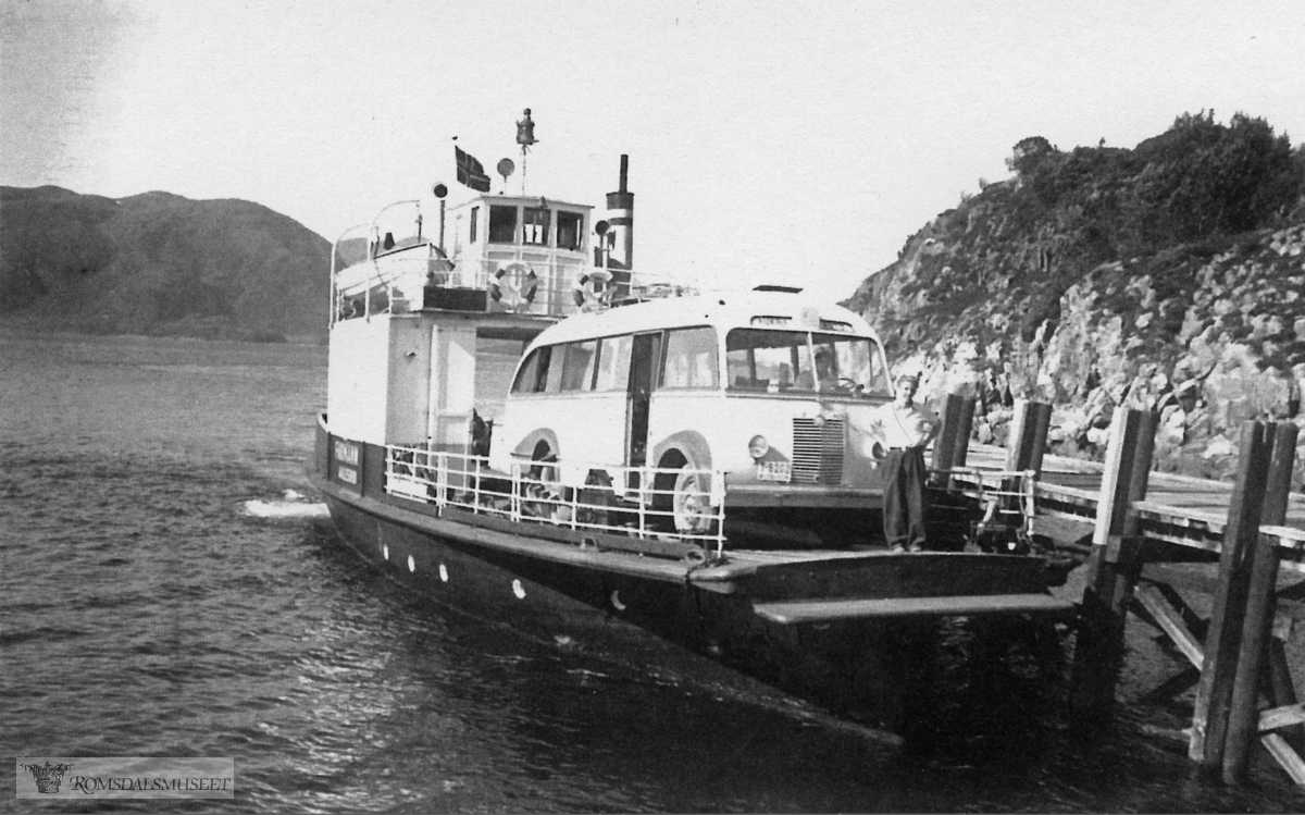 Hollingsholm fergekai. "Farman I".."Farman" var opprinnelig en båt bygd i 1920 og gikk i lokalruter Vatne - Midsund - Ålesund - Molde. I 1936-1937 ble den ombygd til bilferge som de neste 40 åra gikk i forskjellige fergesamband i Møre og Romsdal. 1948 - 1961 gikk den i ruta Aukra - Hollingsholm - Sundsbø (Otrøya). Bussen er antakelig T-8202. Aukra Auto fikk et tysk understell av merket Borgward, krigsmateriell, 1941-modell. Røvik Karosserifabrikk bygde på et busskarosseri med 29 seter. I juni 1949 ble bussen tatt i bruk i ruta Aukra - Molde.