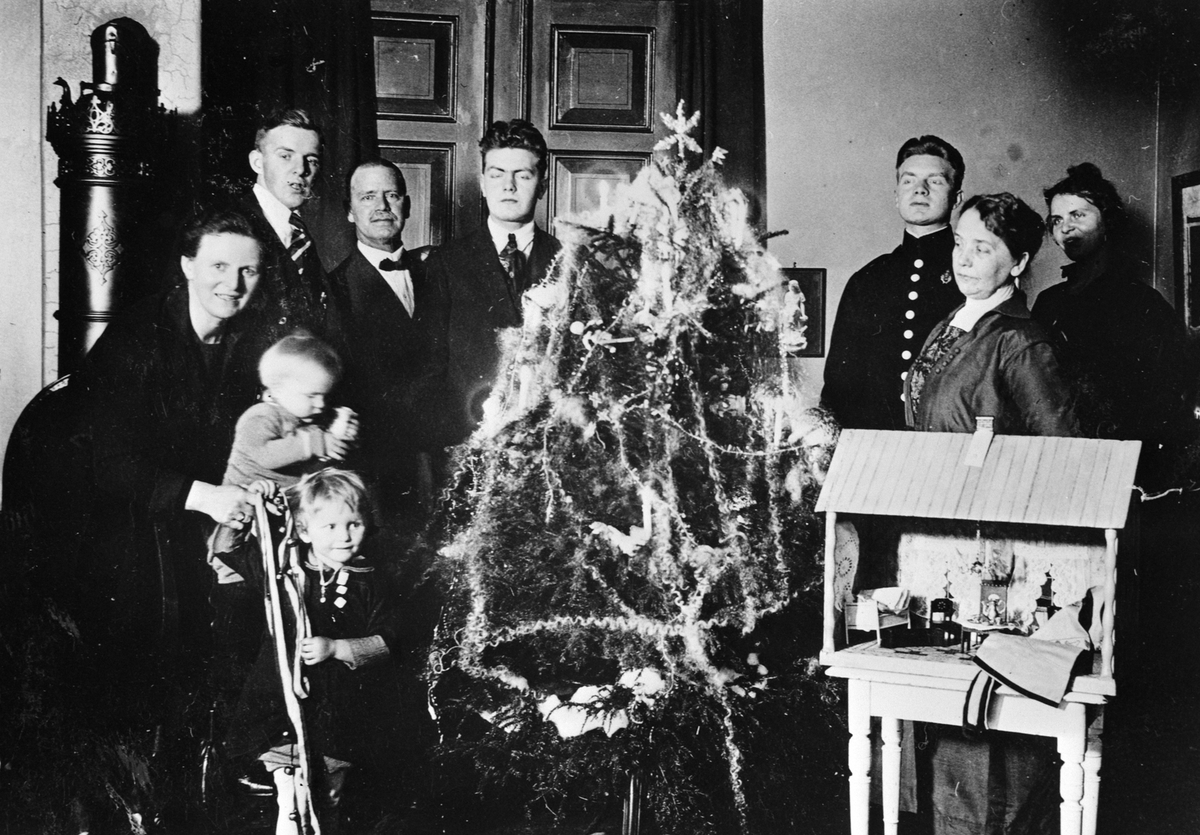 INTERIØR STUE MED JULETRE, JULAFTEN, FAMILIEN LØKEN RUNDT JULETREET, JULEKRYBBE I FORGRUNNEN. 