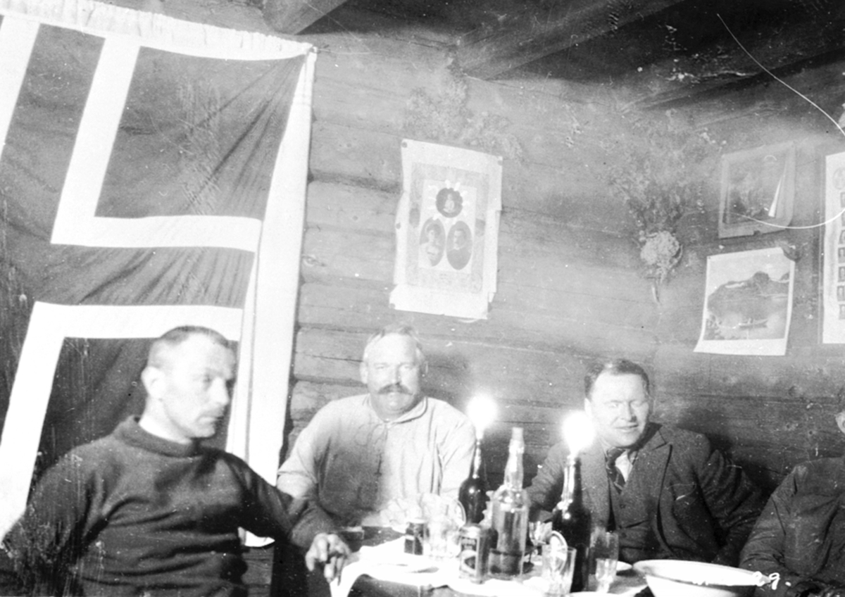Interiør, hytte på Nysætra, Ringsakerfjellet. Tre menn feirer kronprins Ola og kronprinsesse Märthas bryllup. Fra venstre er Grinaker, Nielsen, Aksnes.
