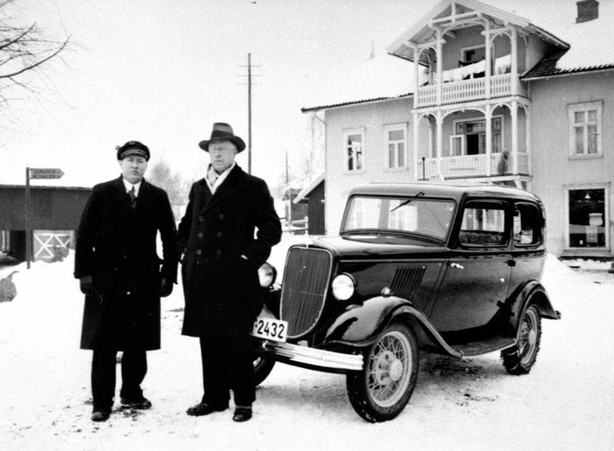 Ringsaker, Moelv, 2 menn foran Moelv elektro, bil med registreringsnummer D-2432. Ford Junior (modell Y) 1933 modell, eier av D-2432 i Norges Bilbok 1935: Inspektør E. Røed, Hamar. til venstre  lensmannsfullmektig Harald J. Røed (1892- 1966) 