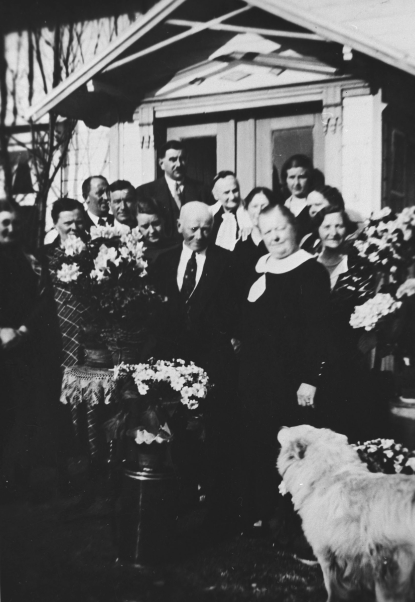 Herr og fru Olsen med menneskegruppe foran hus på Nyborg.