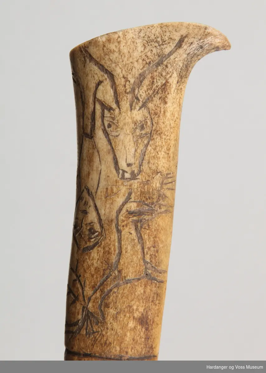 Dekor: Enkle teikningar av reinsdyr, menneske og tre på skaftet.

Knivbladet er av jarn og handtaket av bein.