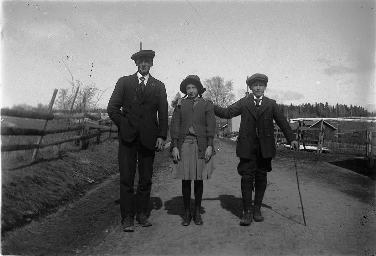Tre personer gående langs vegen i Tingnes, Nes, Hedmark. Fra venstre er Aksel Haakonsen Wiik (1890-1965). De to barna er trolig hans barn Håkon Andreas og Thordis.