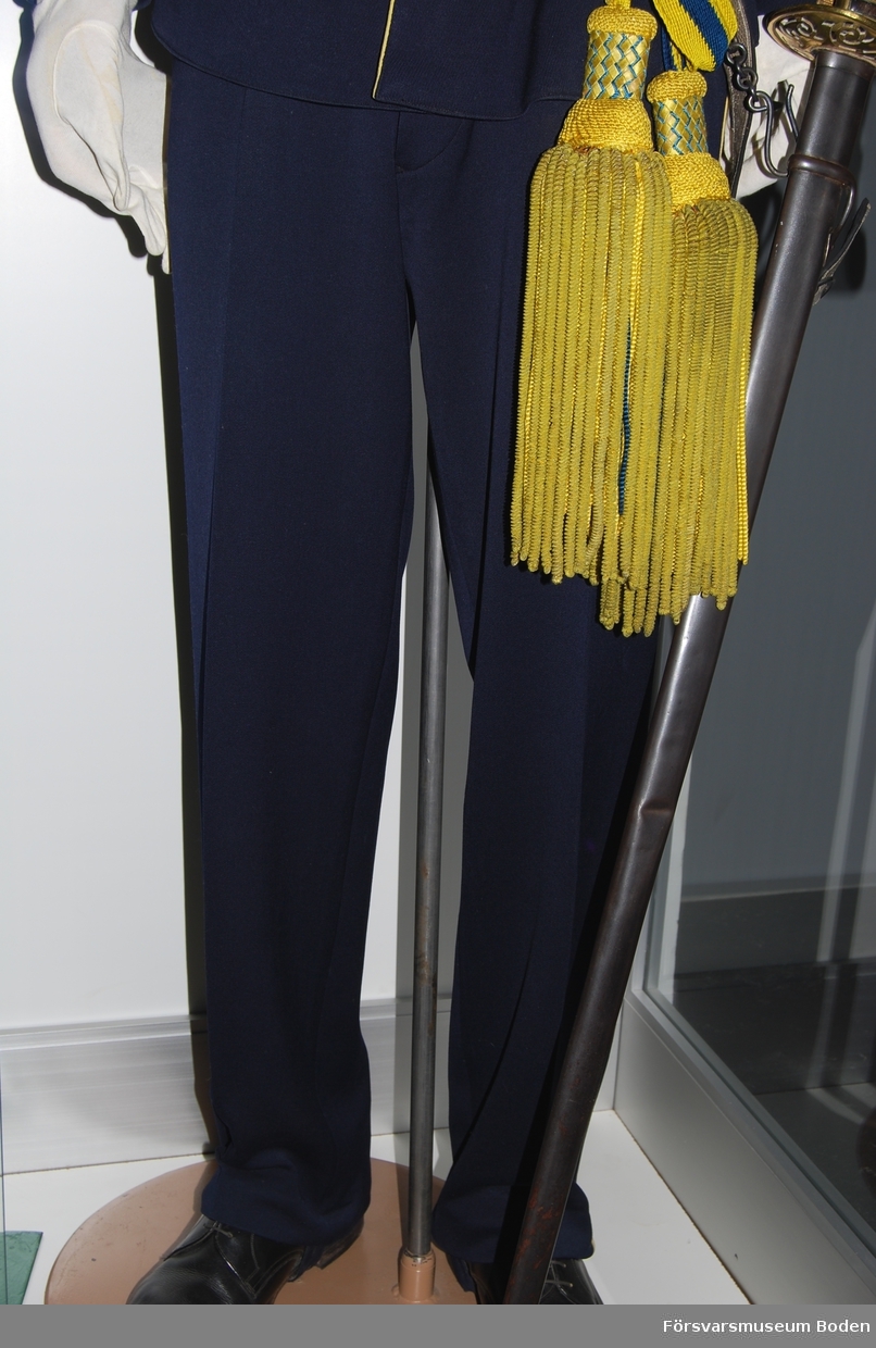 Mörkblått kläde med gula passpoaler (nu kraftigt blekta) längs yttersömmarna. Försedd med hällor, knäppta med dubbla knappar på byxbenens insida vid anklarna.