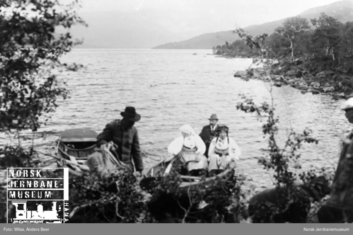 Fem personer, hvorav to kvinner i bunad, med robåt på Store Bjørnevatn i Setesdal