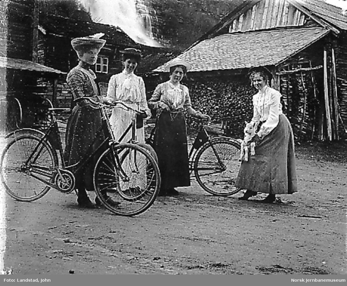 Tre damer med sykkel på et gårdsbruk, trolig navn Framnes