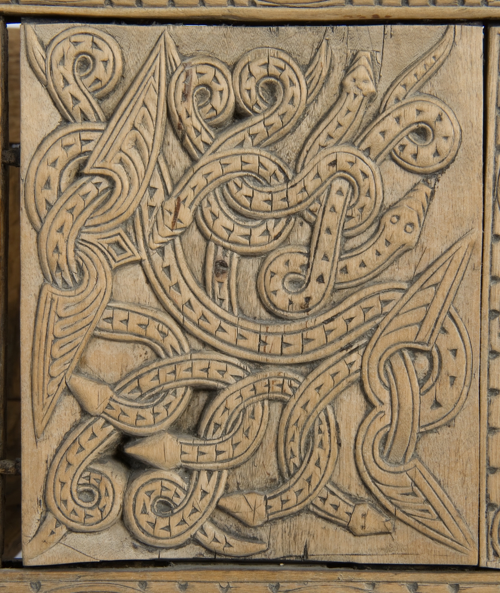 Fire søyler med skåret dyrehode-ornamentikk, sammenføyet med tverrbord og fyllinger. Bunn er åpen foruten to tverrstaver. Hele utsiden er rikt dekorert med utskåret dyr og ranker.