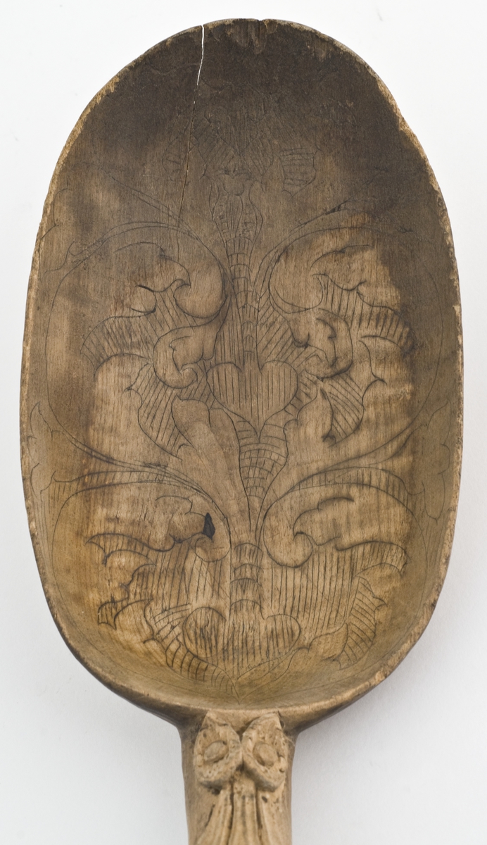 Øse eller sleiv av tre, dekor med akantusranker utskåret på skaftet og innrisset på bladet. 