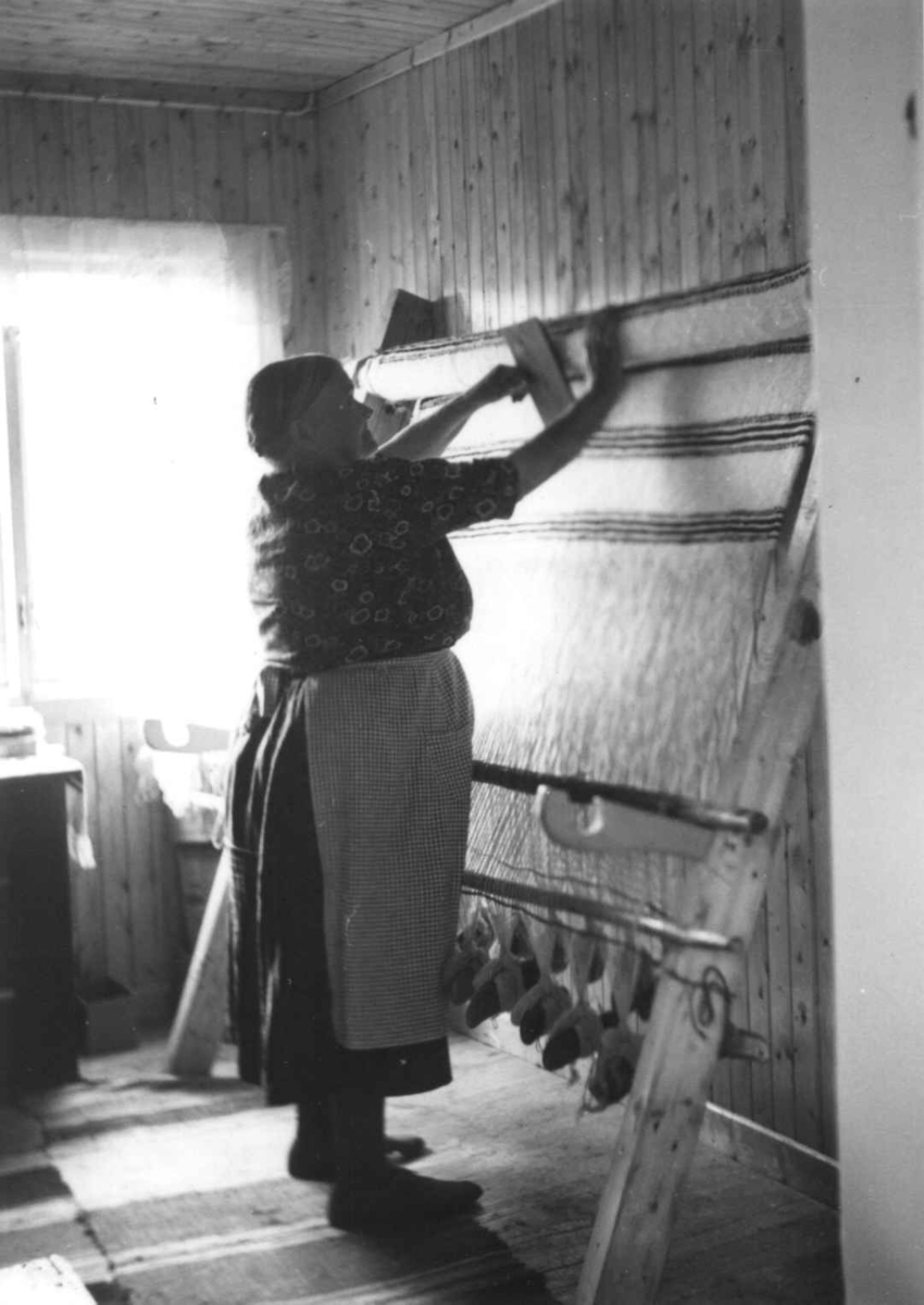 Greneveving (23). Anne Hansen karder opp greneteppet på veven. Manndalen 1955.