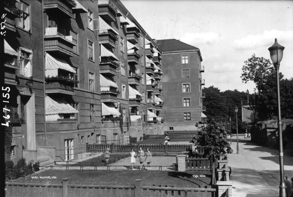 Oslo. Fire jenter i forhagen til bygård med verandaer og markiser.