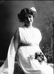 Studioportrett av kvinne i kostyme med hvit kjortel og bloms