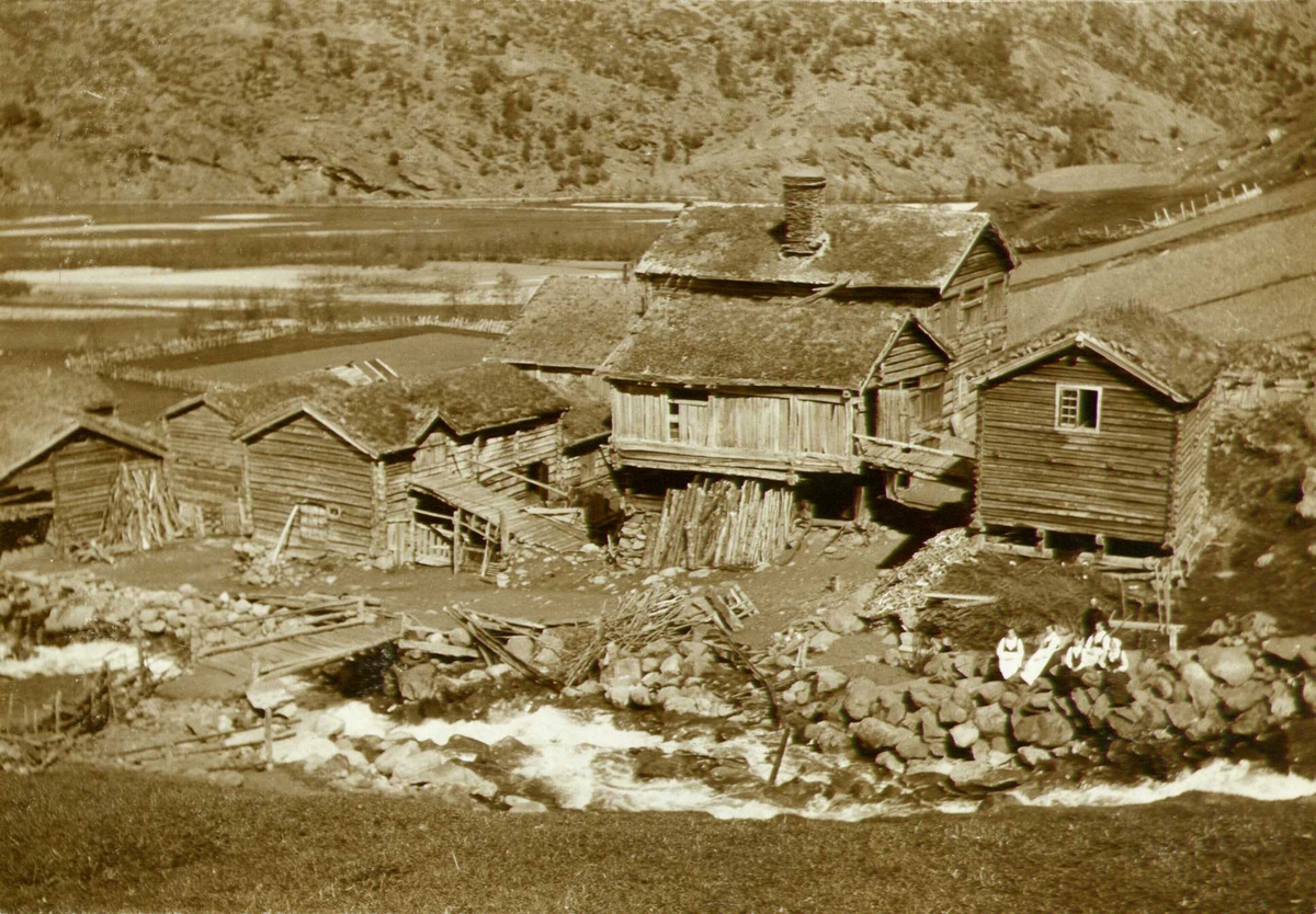 Gårdstun, Glimsdal, Lom, Oppland. Fotografert 1909. Fem kvinner og en mann sittende i forgrunn.