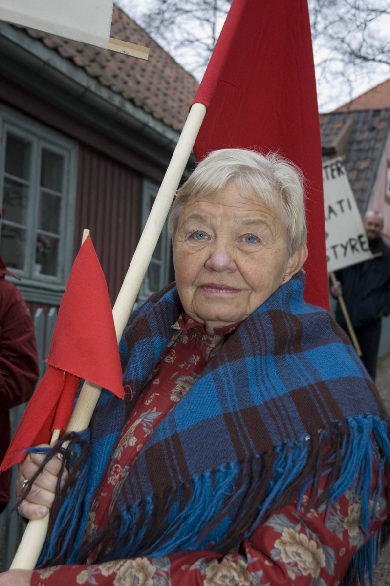1.mai 2006 på Norsk Folkemuseum. Demonstrant med røde flagg og faner i museets gamleby.