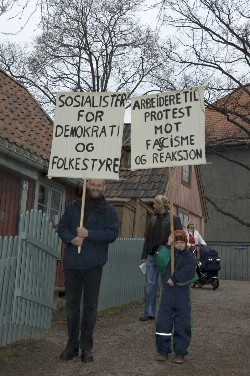 1.mai 2006 på Norsk Folkemuseum. Demonstranter med plakater i museets gamleby, her på Enerhaugen.