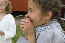 Levendegjøring på museum.Jente som plyster i et gresstrå.
