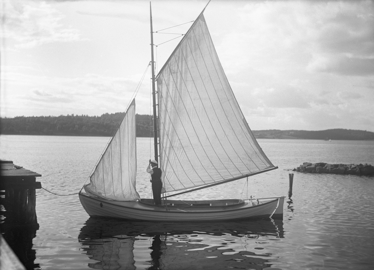 Mann heiser fokken på en liten seilbåt., antagelig et sted i Vestfold. Fotografert 1923.