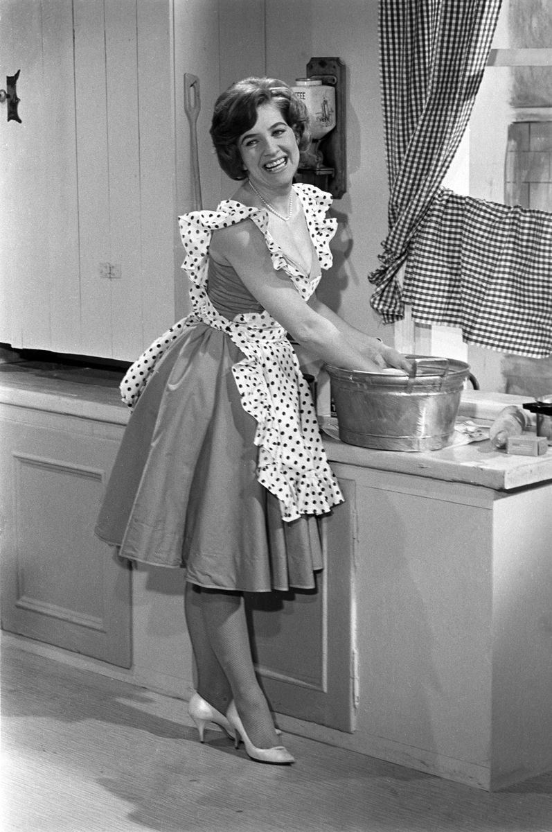 Sølvi Wang synger ved kjøkkenbenken under opptak av TV-programmet "Slagerparaden" i NRK, den 2. desember 1960.