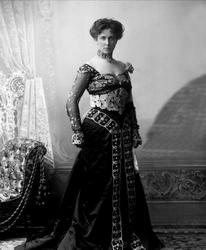 Portrett, kvinne i mørk kjole med chiffonermer. Fru G Dahl.