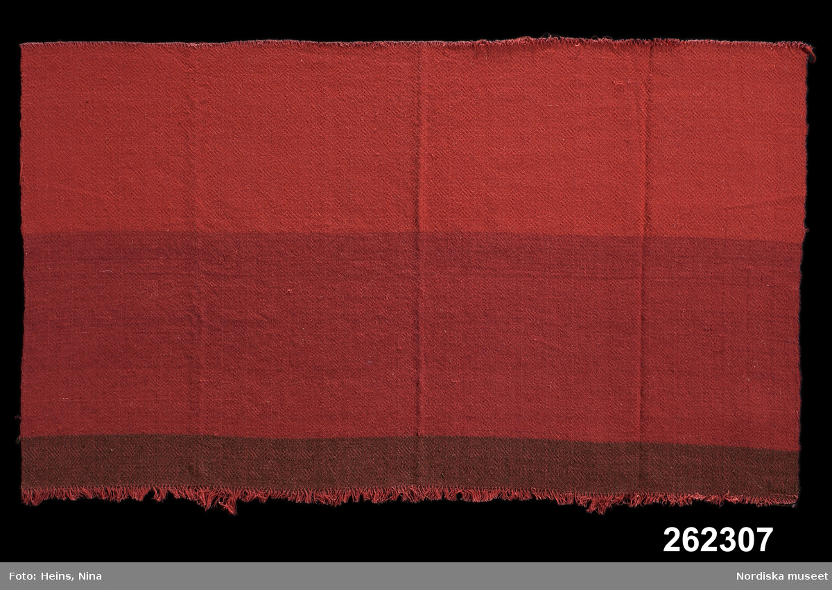 Möbeltyg, prov.
Varp: 2-trådigt S-tvinnat rött bomullsgarn, cirka 200 trådar/10 cm.
Inslag: 1-trådigt Z-spunnet ullgarn, cirka 200 trådar/10 cm.
Kypertvariation, rutornas storlek cirka 2,5 x 2,5 cm. Inslag i tre olika färger för olika mönstereffekt.
Stycke med två stadkanter.
/Berit Eldvik 2002