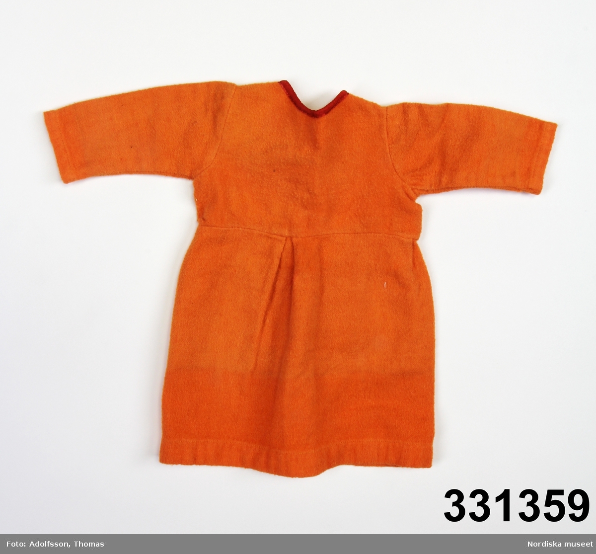 Orange dockklänning med röd halslinning. Två tryckknappar i ryggen.
/Karin Dern 2011-09-13