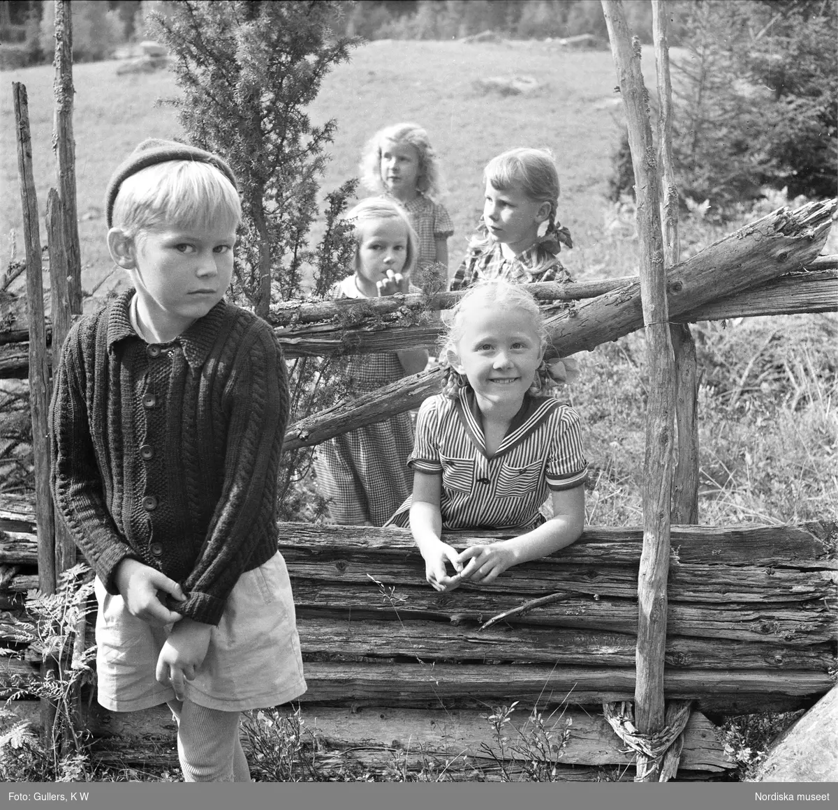 Barn ute i hage vid en gärdesgård.