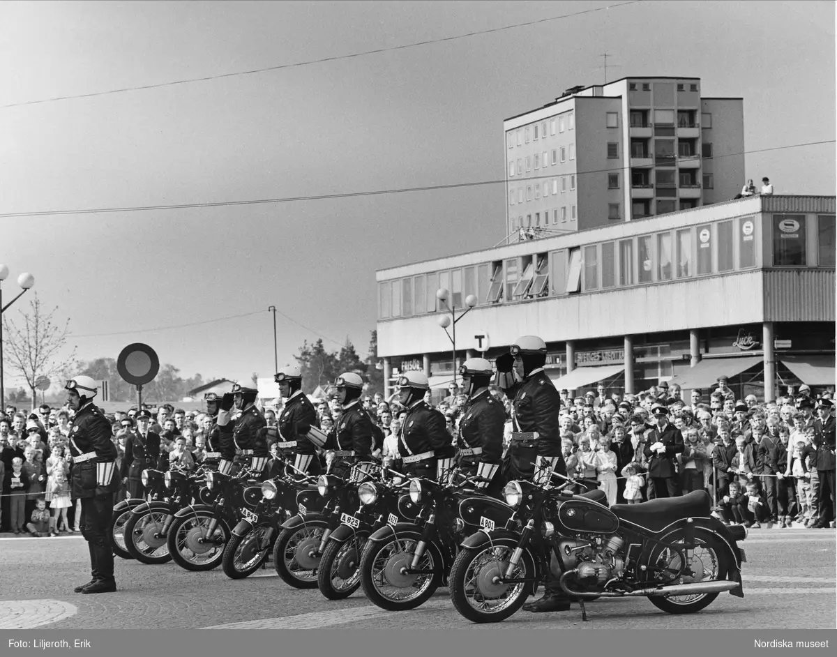 Motocykelpoliser i givakt intill sina motorcyklar i Stockholmsförort 1965, troligen Vällingby centrum.