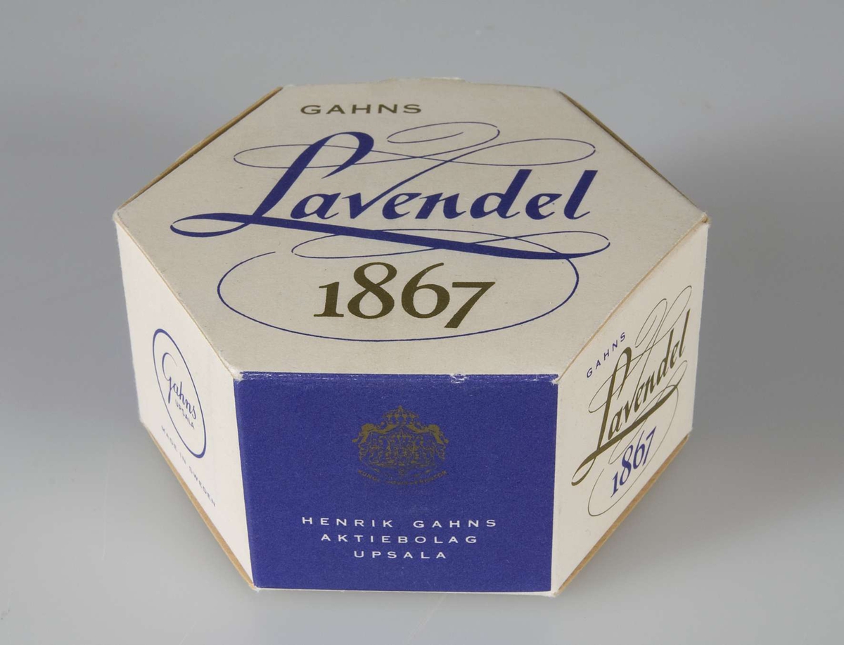 Förpackning med tvål, vit med text i lila och guld "Gahns Lavendel 1867. Henrik Gahns Aktiebolag Uppsala". Innehåller en gulvit rund tvål.