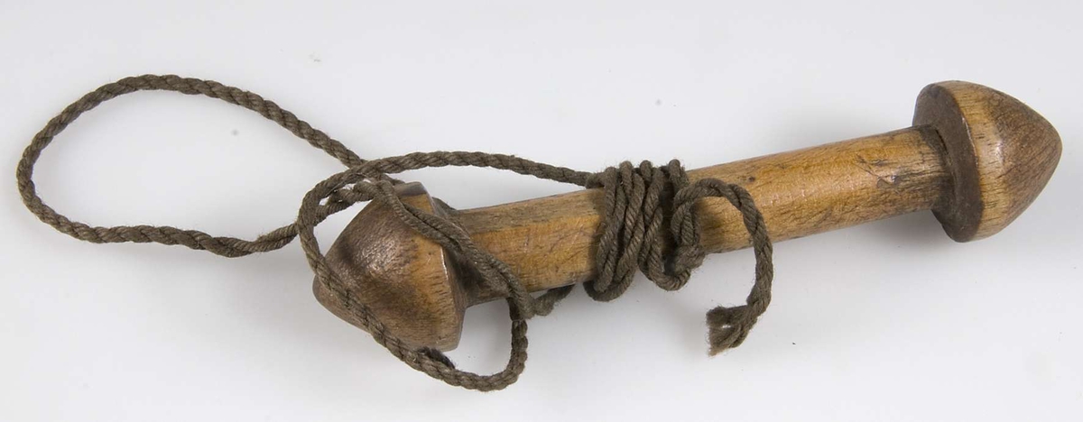 Träpinne med koniska "knappar" i var ände, skurna ur samma stycke, 40 cm lång snodd av brunt bomullsgarn knuten kring mitten.