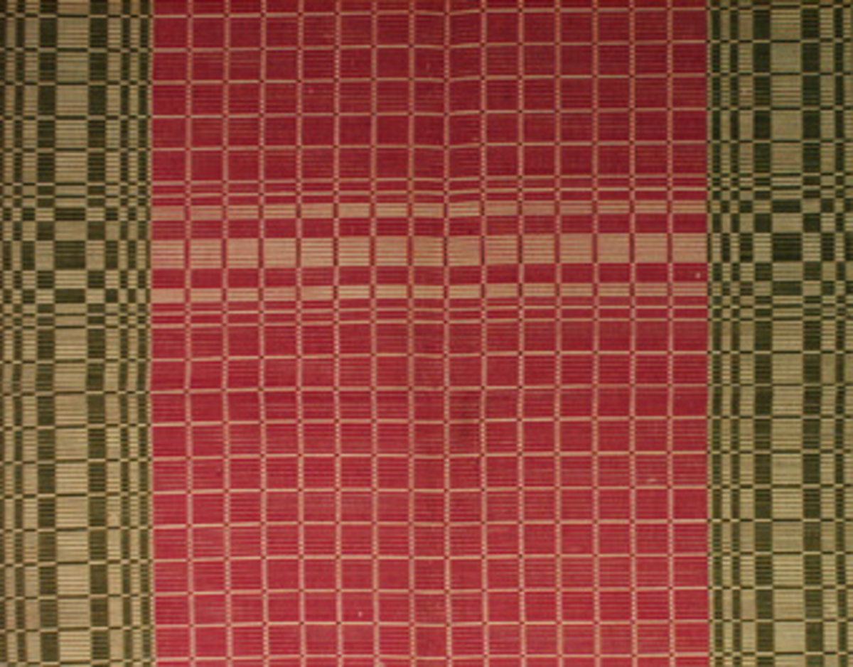 Vävprov ämnat som matta, vävt med bomullsgarn i både varp och inslag. Vävtekniken är rips och färgerna är rött, grönt och vitt. På mattan finns en vaxad tyglapp med vävinformation. Mattprovet är märkt B125.