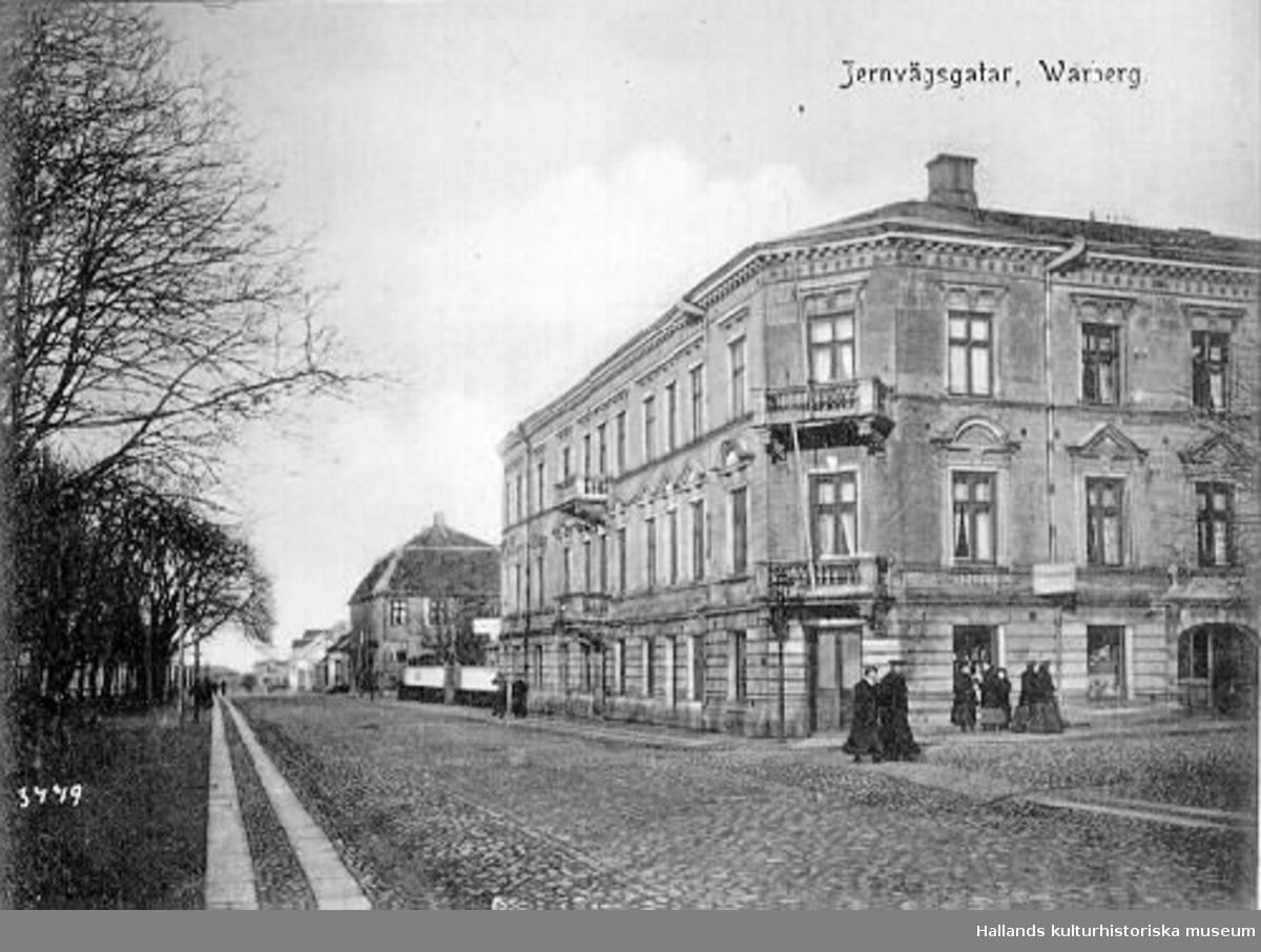 Vykort, "Jernvägsgatan, Warberg". Huset till höger ligger i kvarteret Prosten (nr 7), Västra Vallgatan-Kyrkogatan. Bilden är tagen mot norr. Idag heter gatan Västra Vallgatan.