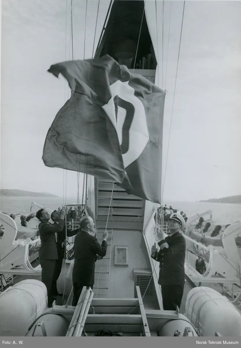 Flaggheising etter overlevering av skipet under prøvetur med passasjerskipet M/S Nordnorge, B/N 550 i Oslofjorden 5. juni 1964. Skipet ble levert av Akers Mek. Verksted til Ofotens Dampskipsselskap.