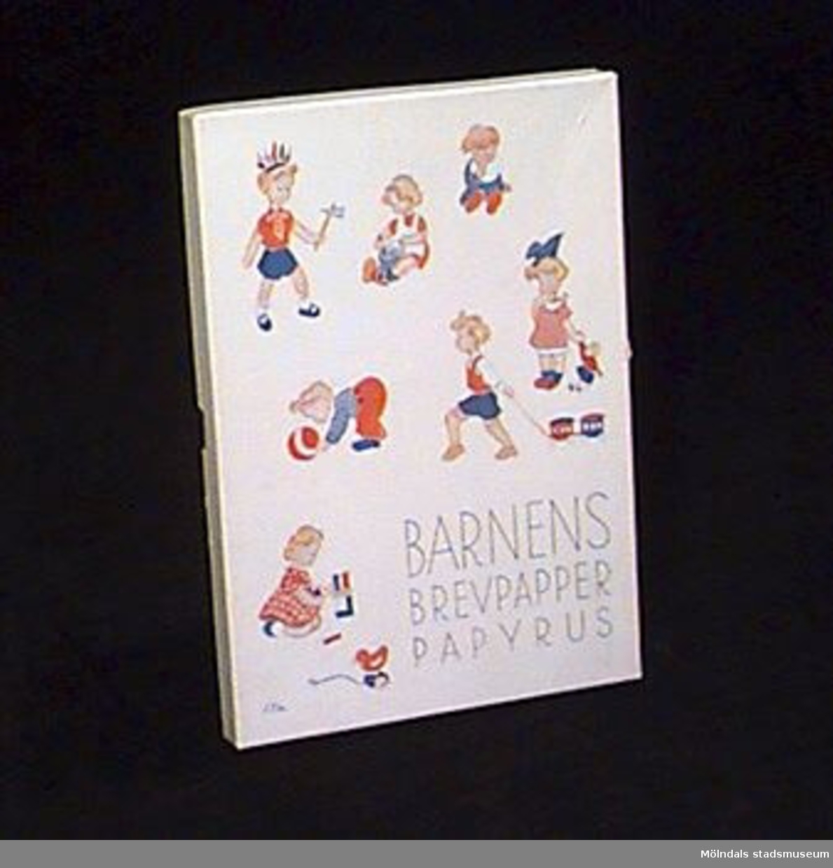 Vit ask med lock. Locket är illustrerat med lekande barn. Blå tryckt text: "Barnens brevpapper", "Papyrus".