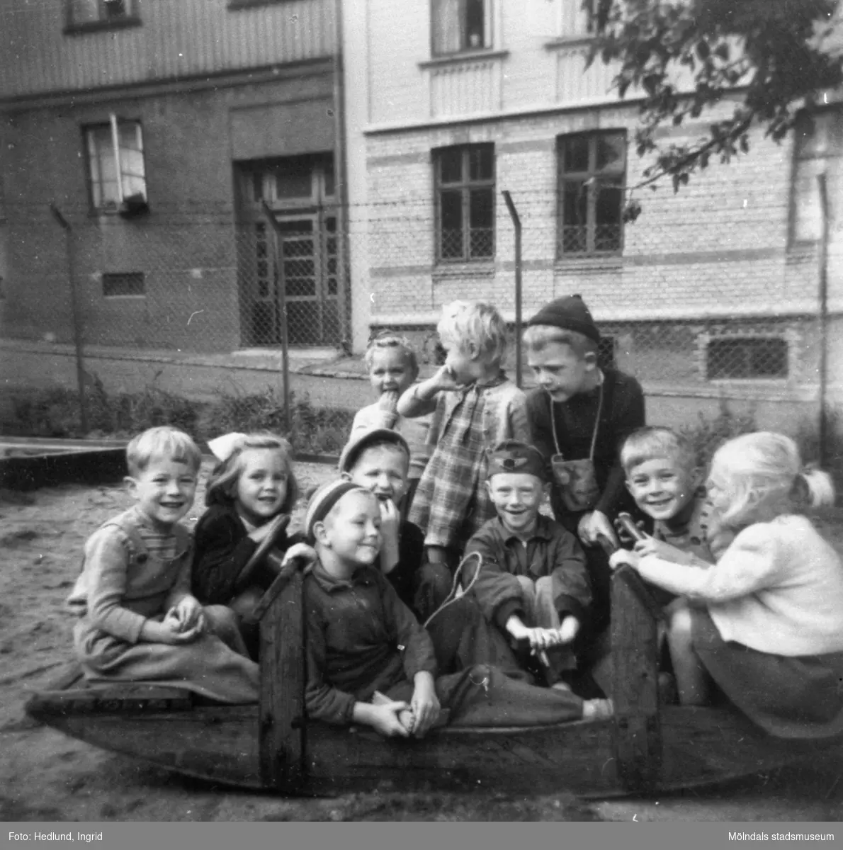 Barn som sitter ute på en lekplats. 1940-tal, plats okänd.