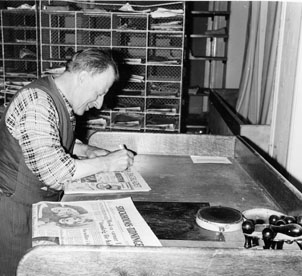 Lantbrevbärare Ruben Carlsson skriver på dagstidningar före brevbäringsturen.