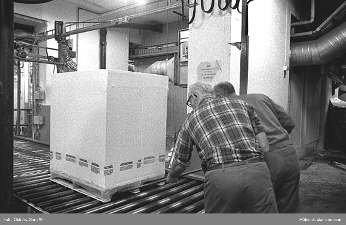 Från vänster: Gotthard Olsson och troligen Tage Carlsson arbetar med pallpackning i pappersfabriken, Byggnad 6. Bilden ingår i serie från produktion och interiör på pappersindustrin Papyrus, 1980-tal.