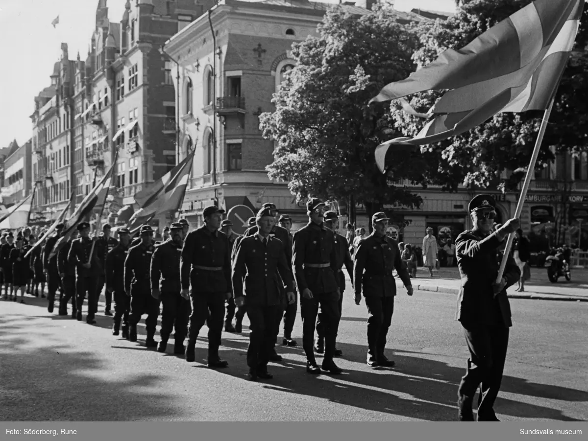 Militärer marscherar med flaggor på Storgatan.