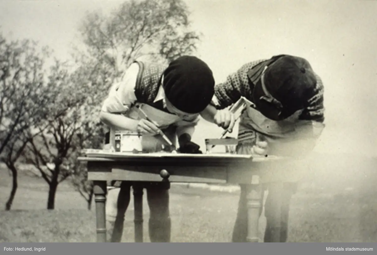 Två barn målar vid ett bord på Bosgårdens barnträdgård, någon gång under åren 1938 - 1945.