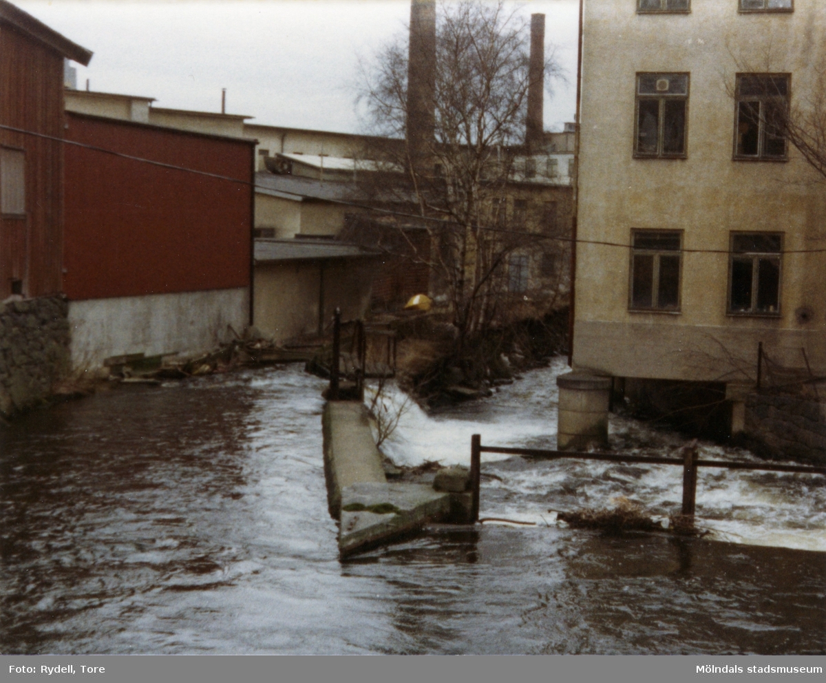 Vy västerut från Rackarebron över Mölndalsfallen, 1970-tal. Till vänster ses ett gammalt magasin från 1800-talet och till höger byggnaden "Strumpan" (efter Viktor Samuelsons fabrik), Kvarnbygatan 10-14.