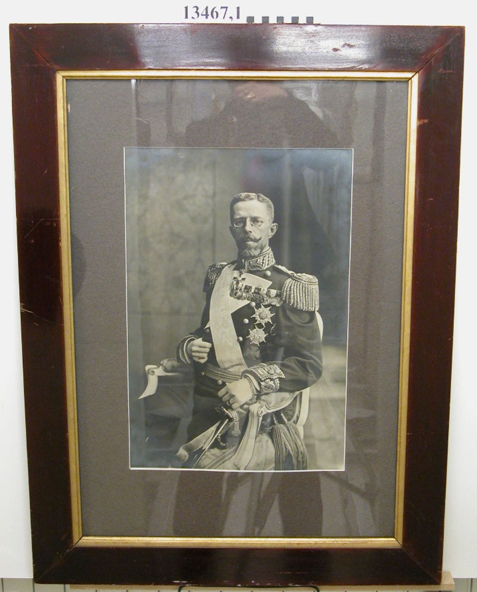 Fotografi inom glas och ram.Porträtt av H.M. konung Gustaf V.
Har tillhört pb Dristigheten.
Neg.nr A 761 2:3