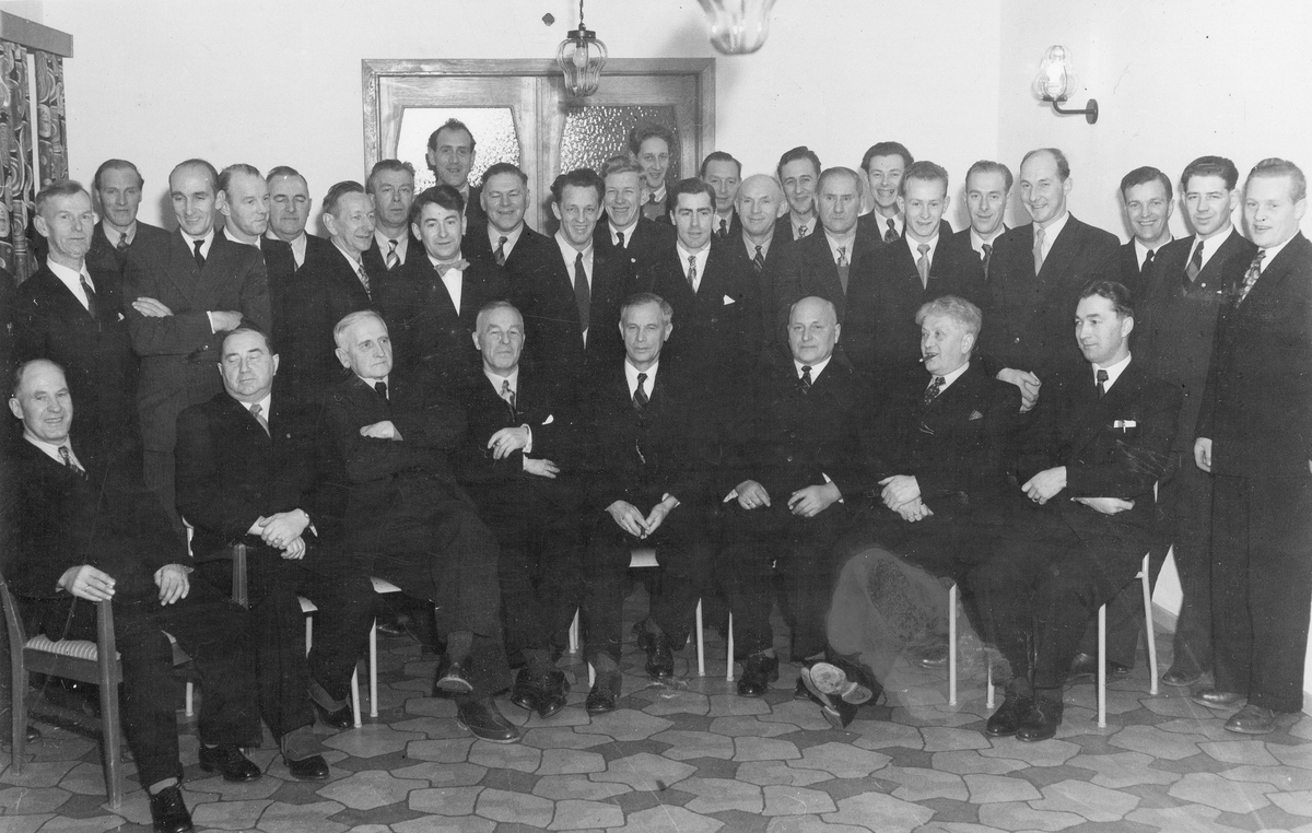 Gruppebilde av menn på innvielsesfest hos HORB, i forbindelse med de nybygde anleggene på Torvet og Sama, vinteren 1955-1956.