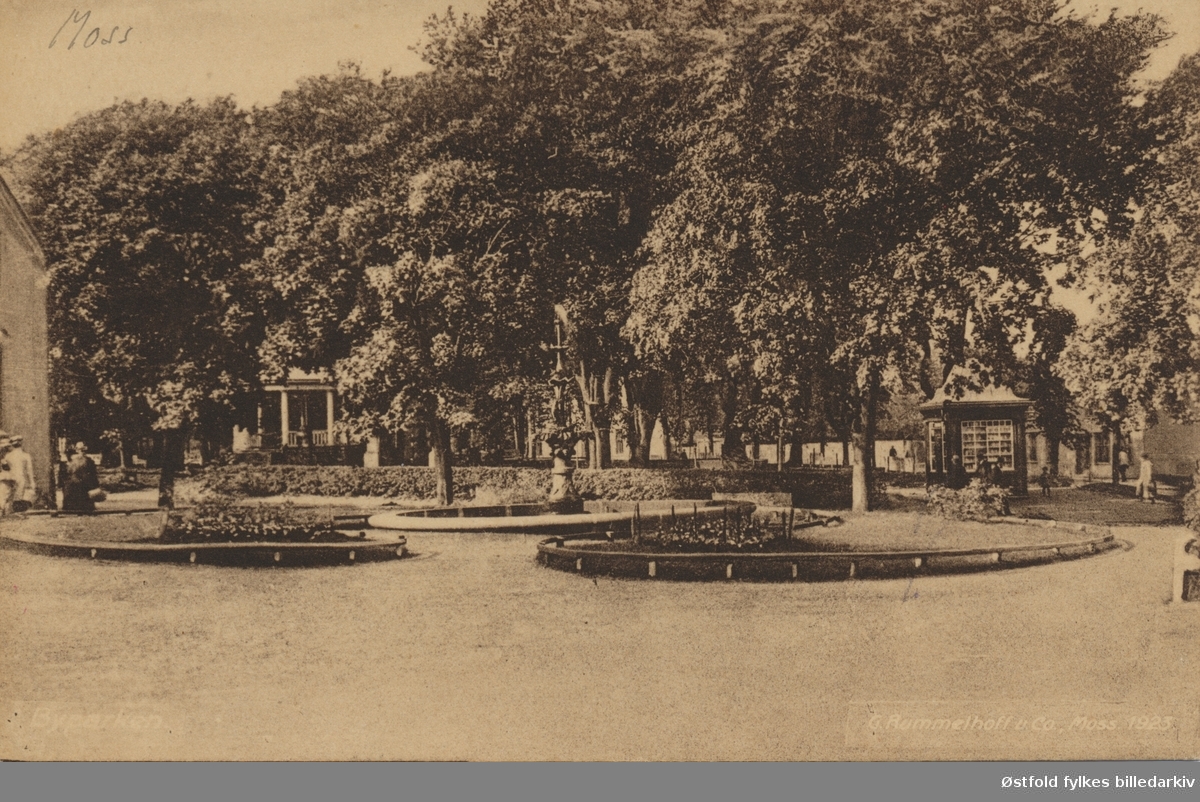 Kirkeparken  i Moss med den gamle fontenen som ble fjernet i 1936. Paviljongen og en kiosk. Tittel på postkortet: "Byparken."