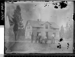 Bolighus med en mann, to kvinner og tre barn i forgrunnen.