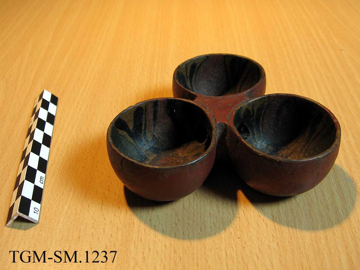 Tre mindre beger - laget av ett trestykke. Munkepanneform. Hull mellom begrene. Rødbrun maling på utsiden, rosemaling oppi begrene.