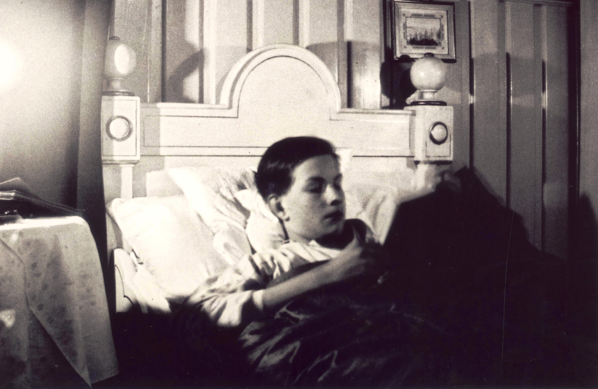 Foto av Niels Frederik Aall som ligger i seng og leser bok