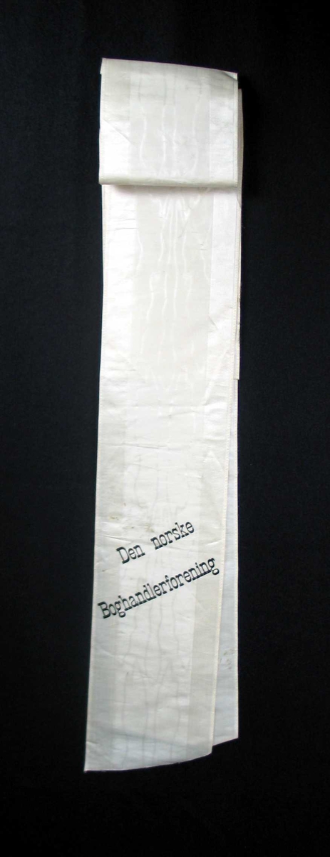 Begravelsessløyfe i hvit silke med svart skrift.