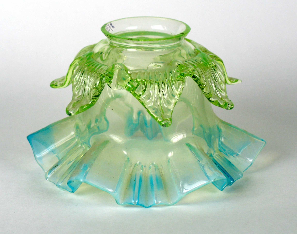 Lampeskjerm i glass med turkis bølget kant nederst og en lys grønn bladformet kant øverst.
